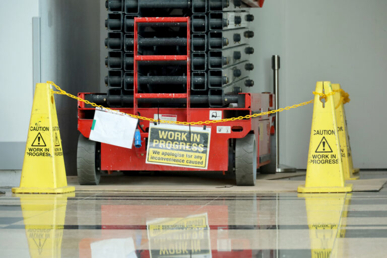 Elevated aerial scissor lift, electric ladder in the corner of the room with the words work in progress